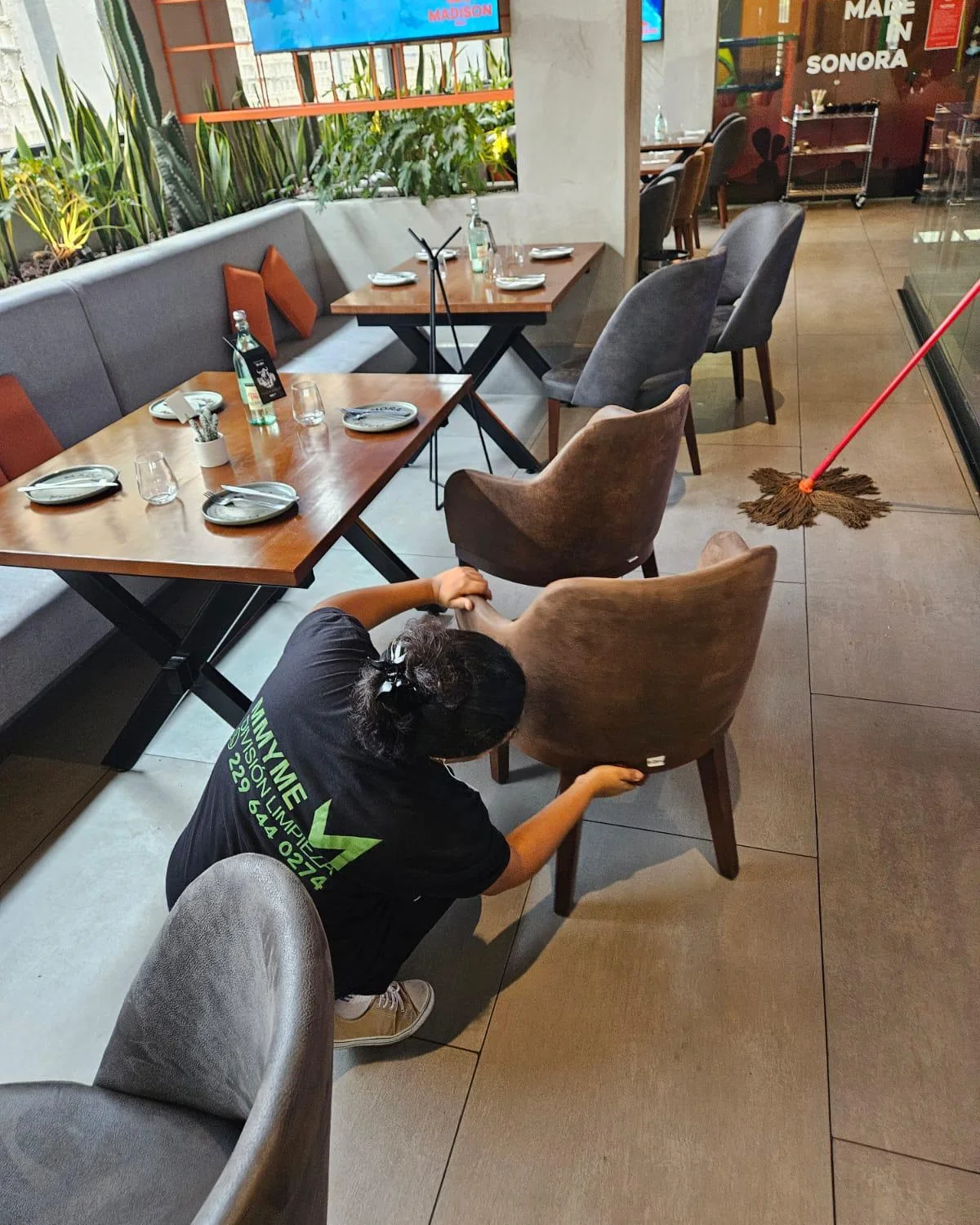 Colaboradora de MMYME limpiando a detalle una silla en un restaurante